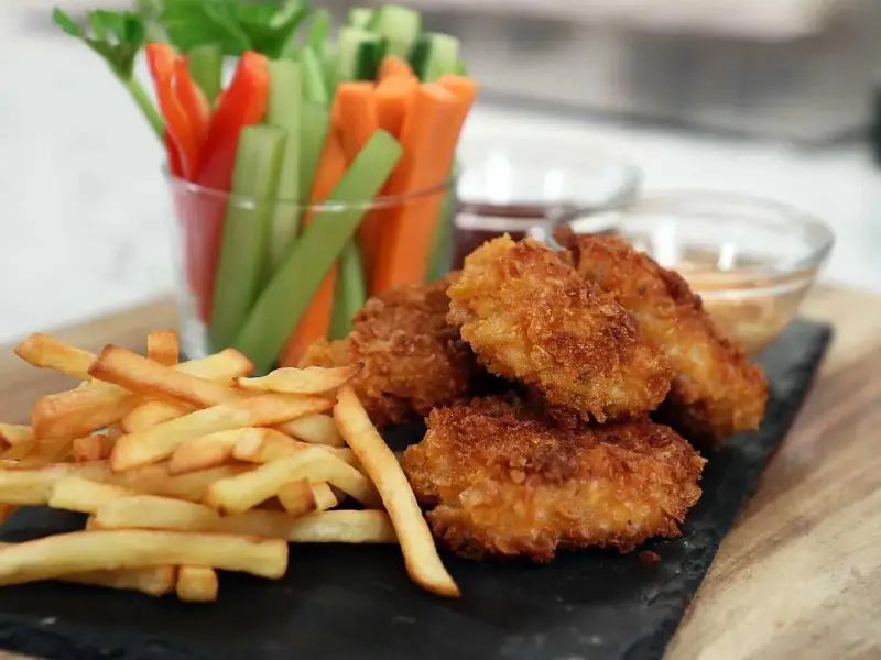 Krispiga chicken nuggets med pommes frites och grönsaksstavar. Perfekt för en mysig kväll!